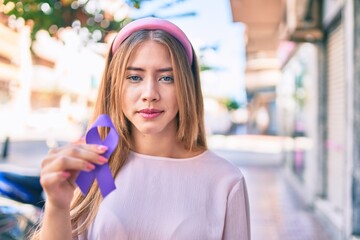 Young caucasian girl with serious expression holding purple ribbon walking at the city.