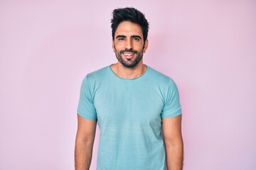 Handsome hispanic man with beard wearing casual clothes with a happy and cool smile on face. lucky person.