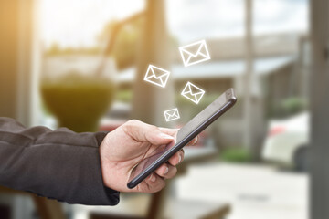 Hand holding using mobile phone with email icon on screen. Concept of business communication technology.