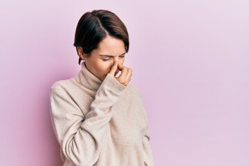 Young brunette woman with short hair wearing casual winter sweater tired rubbing nose and eyes...