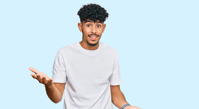Young arab man wearing casual white t shirt smiling cheerful with open arms as friendly welcome, positive and confident greetings