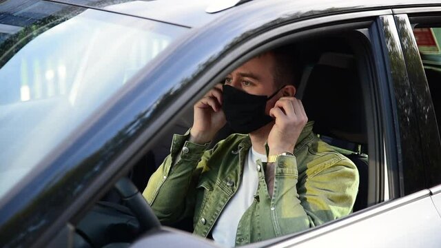 Taxi driver in mask or wearing a mask and fastening his seat belt. Driver in mask. Concept new normality and Covid-19.