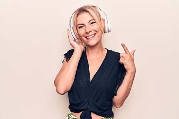 Young beautiful blonde woman listening to music using headphones over white background smiling...