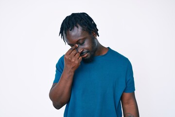 Young african american man with braids wearing casual clothes tired rubbing nose and eyes feeling fatigue and headache. stress and frustration concept.