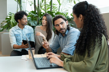 Obraz premium Professional latin business team with laptop planning business future, checking reports inside coworking office. Teamwork, corporate, planning, strategy concept..