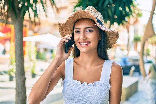 Young latin girl wearing summer style talking on the smartphone at street of city.