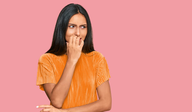 Young brunette arab woman wearing casual clothes looking stressed and nervous with hands on mouth biting nails. anxiety problem.