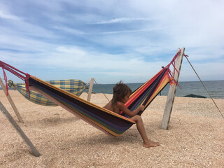 Fototapeta premium a child on the sea is sitting in a hammock and stuck out his leg