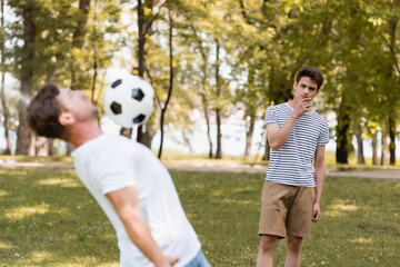 Naklejka premium selective focus of pensive teenager son looking at father playing football