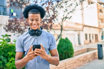 Fototapeta na wymiar Young african american man smiling happy using smartphone and headphones at the city.