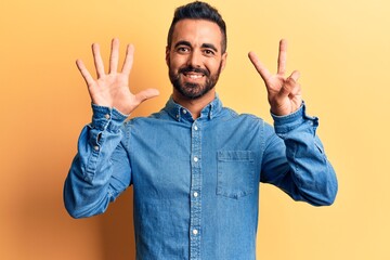 Naklejka premium Young hispanic man wearing casual clothes showing and pointing up with fingers number seven while smiling confident and happy.