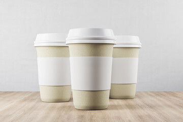 Three disposable white paper cup of coffee on wooden table.