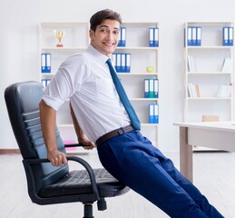 Young businessman doing sports stretching at workplace