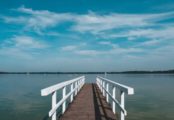 lonely wooden bridge at a calm lake with a cloudy sky