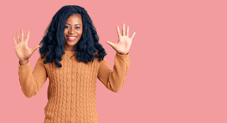 Beautiful african american woman wearing casual  sweater showing and pointing up with fingers number ten while smiling confident and happy.