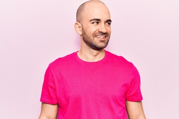 Young handsome bald man wearing casual t shirt looking to side, relax profile pose with natural face and confident smile.