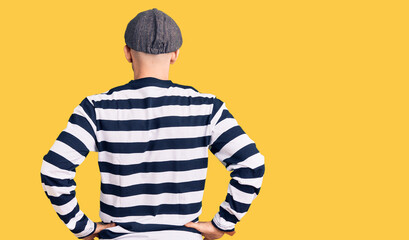 Young handsome man wearing burglar mask standing backwards looking away with arms on body