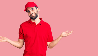 Fototapeta premium Young handsome man with beard wearing delivery uniform smiling showing both hands open palms, presenting and advertising comparison and balance