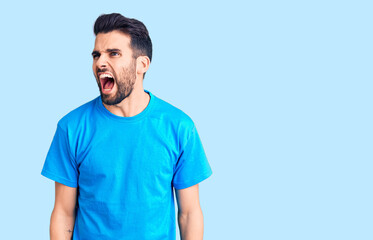Fototapeta premium Young handsome man with beard wearing casual t-shirt angry and mad screaming frustrated and furious, shouting with anger. rage and aggressive concept.
