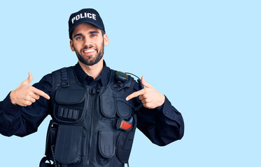 Young handsome man with beard wearing police uniform looking confident with smile on face, pointing oneself with fingers proud and happy.