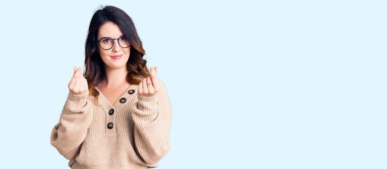 Beautiful young brunette woman wearing casual clothes and glasses doing money gesture with hands, asking for salary payment, millionaire business