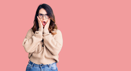 Beautiful young brunette woman wearing casual clothes and glasses afraid and shocked, surprise and...