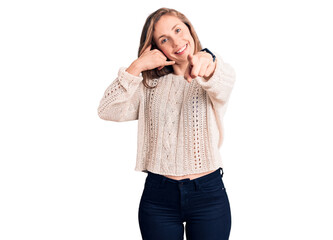 Young beautiful blonde woman wearing casual sweater smiling doing talking on the telephone gesture...