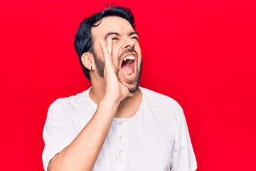 Young hispanic man wearing casual clothes shouting and screaming loud to side with hand on mouth. communication concept.