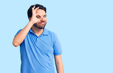 Fototapeta premium Young hispanic man wearing casual clothes doing ok gesture with hand smiling, eye looking through fingers with happy face.