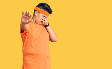 Little boy kid wearing sportswear covering eyes with hands and doing stop gesture with sad and fear expression. embarrassed and negative concept.