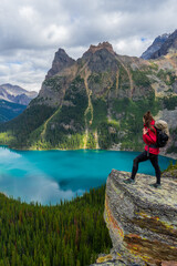 Hiker woman on top of Opabin Prospect overlooking Lake O'Hara and Mary Lake with the Canadian Rockies in the background. British Columbia, Canada