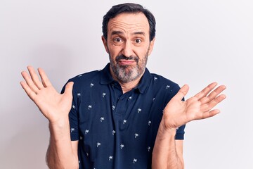 Middle age handsome man wearing casual polo standing over isolated white background clueless and...