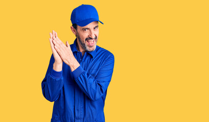 Middle age handsome man wearing mechanic uniform clapping and applauding happy and joyful, smiling...
