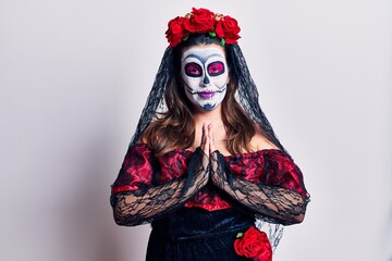 Young woman wearing day of the dead costume over white praying with hands together asking for forgiveness smiling confident.