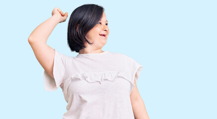 Brunette woman with down syndrome wearing casual white tshirt dancing happy and cheerful, smiling...