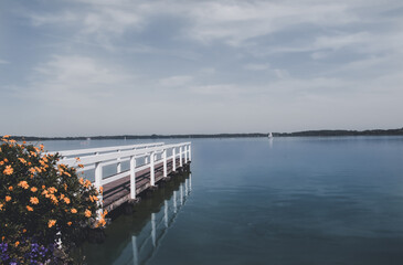 Fototapeta premium lonely wooden bridge at a calm lake with a cloudy sky