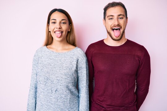 Beautiful couple wearing casual clothes sticking tongue out happy with funny expression. emotion concept.