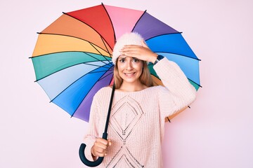 Young brunette woman under colorful umbrella stressed and frustrated with hand on head, surprised and angry face