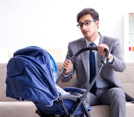 Businessman looking after newborn baby at home and teleworking