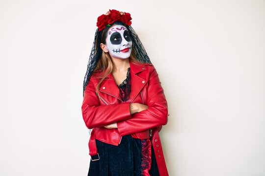 Woman wearing day of the dead costume over white looking to the side with arms crossed convinced and confident
