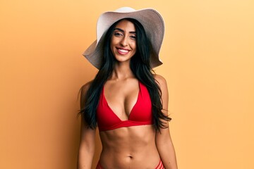 Beautiful hispanic woman wearing bikini and summer hat with a happy and cool smile on face. lucky person.