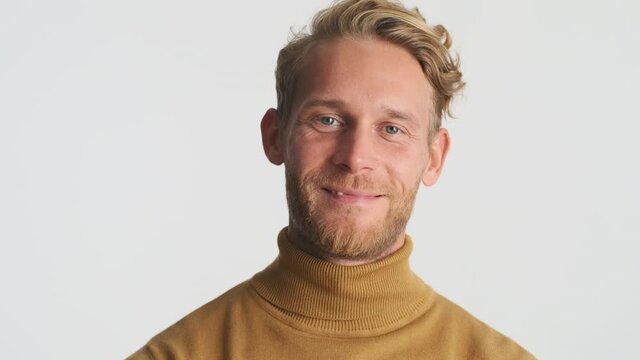 Handsome blond bearded man happily posing on camera over white background