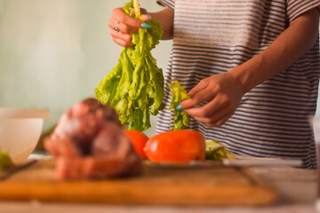 Person preparing salad of tomatoes and lettuce, meat close-up on a cutting board