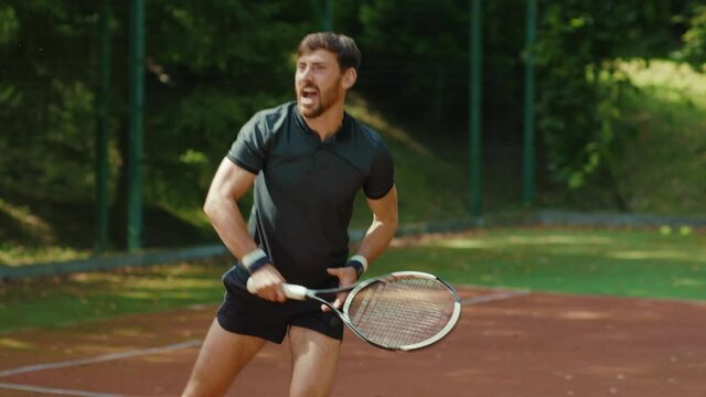 Funny young man playing tennis on a court sunny day holding tennis racket fall down competition playing sportswear match sport health equipment racket fit close up slow motion
