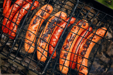 BBQ with fiery sausages hotdog on the grill outdoor picnic preparing hot food to be served at a local outdoor fair on the picnic. Top view