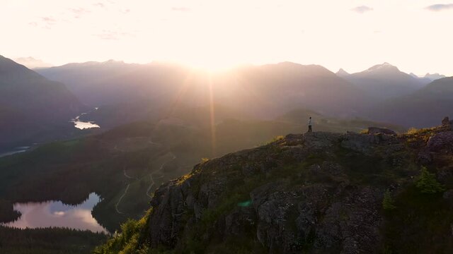 Man Standing On The Summit Of A Mountain At Sunrise