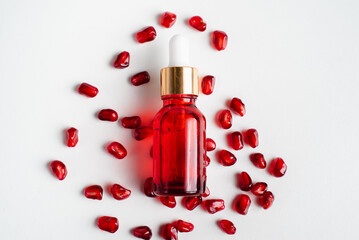 Serum bottle containing organic pomegranate seed oil extract on white background. Cosmetic natural...
