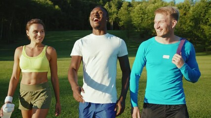Funny trio of attractive well-trained people friends communicating while walking to the gym. Group of healthy-looking bodybuilders. Workout. Active lifestyle.