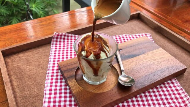Pouring coffee on vanilla ice cream to make an affogato coffee