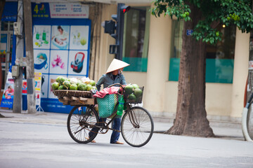 Fototapeta na wymiar Hanoi, Vietnam - November 21, 2019: Street vendors are hurriedly cycling across the street to find customers in the small neighborhood in Hanoi, Vietnam